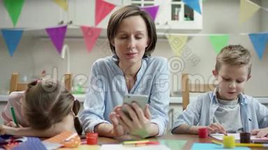 母亲和她的孩子坐在一起，孩子们在做节日的工艺品，微笑着