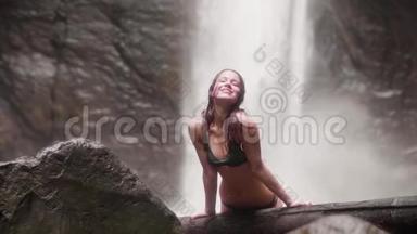 布吕内特<strong>女士</strong>，湿发和<strong>比基尼</strong>微笑，在流动的山瀑布背景前摆相机