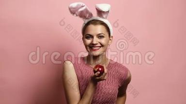 粉红背景的复活节兔子女孩。 复活节快乐。 复活节时戴兔子耳朵的漂亮年轻女人。 很漂亮