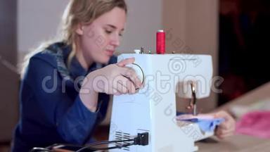 一位年轻的女裁缝搭起缝纫机，开始缝衣服。 专注于缝纫机，慢动作