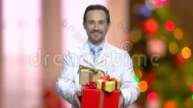 微笑的医生在圣诞节背景下送礼物。