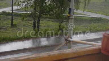外面`下着大雨。 从阳台可以看到<strong>街景</strong>。 树在一阵风下弯曲。 在沥青流水上..