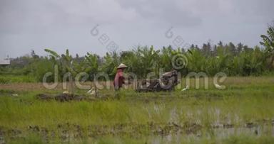 亚洲农民用手拖拉机耕作他的稻田，稻田里浸满了水，农业在白天劳作