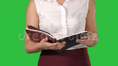 女人手里拿着笔记本，翻页，在绿色的屏幕上看着它，铬钥匙。