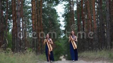 两个女竖琴手在森林里散步，在松树的背景下演奏竖琴。