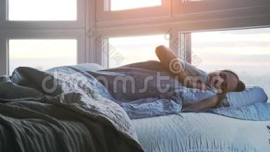 美丽浪漫的黑发女人躺在床上，早上在房间里藏着毯子打哈欠。 慢动作