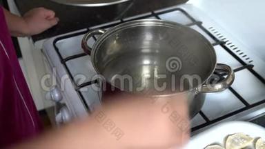厨房里的一个女人在<strong>煤气灶</strong>旁边的一个锅里煮饺子
