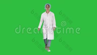 微笑的儿科医生双手放在制服口袋里，走在绿色的屏幕上，铬钥匙。