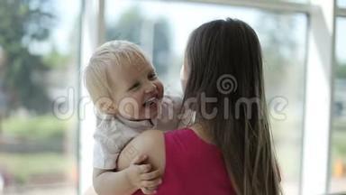 可爱的金发婴儿在妈妈`怀里笑。