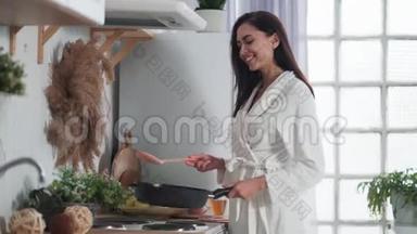 穿着<strong>白色浴袍</strong>在厨房做饭的年轻女子