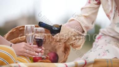 两个女人坐在毯子上，把红酒倒在杯子里-托斯卡纳