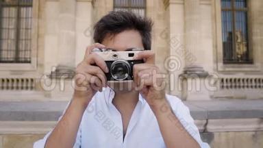 巴黎，法国，2019年4月。 在卢浮宫博物馆背景下，穿着白色衬衫的年轻人用摄像机拍摄照片
