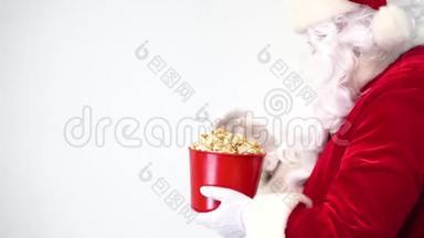 白色背景上的圣诞老人带着一桶红色的爆米花。 吃爆米花和看电影，提供爆米花。