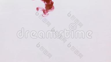 红色油漆滴在水中的混沌运动。 墨水在水里。 特写镜头。