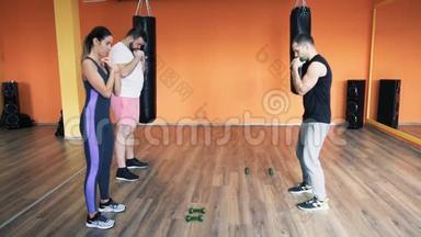 私人教练向一个胖男人解释，苗条的女孩在<strong>健身</strong>房。 哑铃训练。 个人<strong>减肥</strong>训练