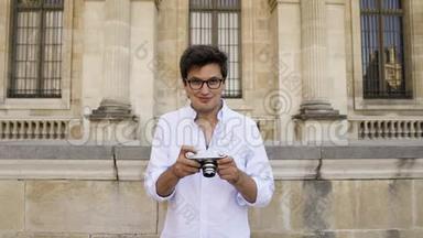 巴黎，法国，2019年4月。 在卢浮宫博物馆背景下，穿着白色衬衫的年轻人用摄像机拍摄照片