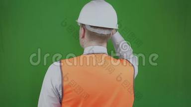 工程师或建筑工人站在背后看着建筑工程。 铬化。 戴着白色头盔的头儿