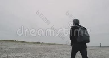 在寒冷的天气里，在海边，一个快乐的人在一场雨后穿过灰色的海滩。