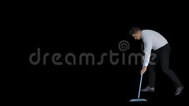 在扫地后，一个拇指拿着扫帚的男人，穿着正式的衣服或商业服装