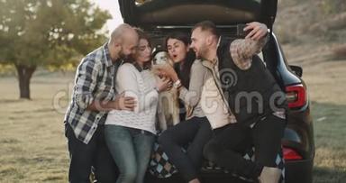有魅力的夫妻在一次<strong>汽车</strong>旅行中有一个停留，用手机拍摄一些自拍照片，他们坐在<strong>汽车</strong>的<strong>后备箱</strong>里。