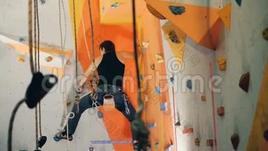 一个人爬在一个中心的橙色墙上，靠近。
