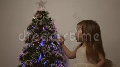 <strong>小</strong>孩子在<strong>儿童房</strong>的圣诞树旁玩耍。 女儿在圣诞树上检查花环。 美丽的人造的