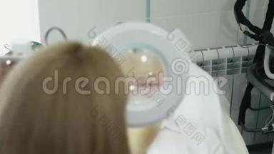 美容师通过化妆品放大镜检查病人嘴唇周围的区域