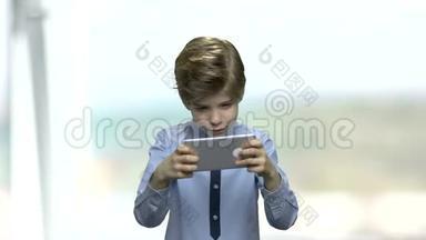 快乐的<strong>男孩</strong>在他的智能手机上<strong>玩游戏</strong>。