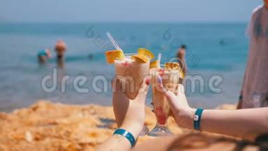 在埃及海边和海滩的背景下，两个女孩手中的异国鸡尾酒。