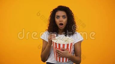 兴奋的非裔美国妇女吃爆米花和看有趣的电影
