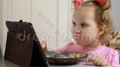 小女孩吃早餐，涂酸奶，并在平板电脑屏幕上锁定视频。