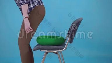 女人坐在矫形枕头上的椅子上的蓝色背景，痔疮的概念接近
