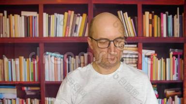 思考人戴眼镜看书在家书库的书柜背景。 在舒适的家中阅读文档的男人