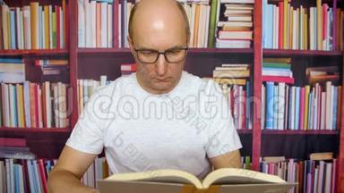 一个戴眼镜的人，在书架背景下的家庭办公室桌上看书