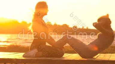 两个年轻漂亮的女孩在日出或日落前在海边的<strong>沙滩</strong>上脱衣服