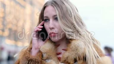 迷人的快乐迷人的女人，穿着狐狸毛大衣，在户外和电话交谈