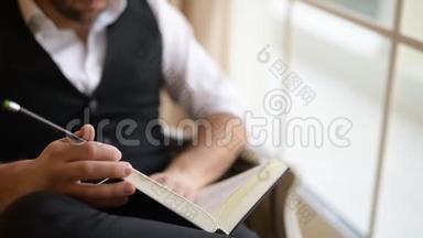 商人坐在扶手椅上翻书的特写镜头。