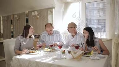 概念-快乐的朋友在餐厅吃喝。 四个朋友在餐厅吃肉喝红酒