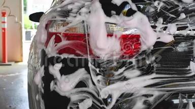 洗车。 洗车机清洗汽车。 车上覆盖着白色的冲洗泡沫..
