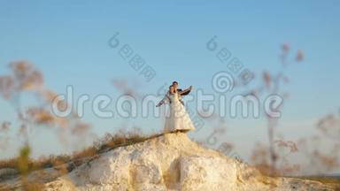 <strong>美丽</strong>的新娘和新郎站在山上，在蓝天下翱翔，微笑着。 情侣婚礼<strong>之旅</strong>