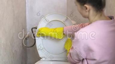 女人用黄色橡胶手套用海绵清洗白色马桶