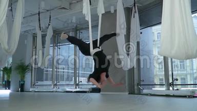 <strong>身材</strong>魁梧的女人头朝下吊在现代健身中心的<strong>瑜伽</strong>吊床上，地板很大
