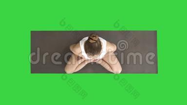 穿着白色的女人在绿色屏幕上用莲花姿势练习瑜伽，Chroma键。