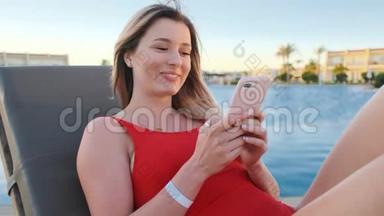 女人在海滩的躺椅上用手机。 穿着<strong>红色</strong>比基尼的夏天女孩上网，发短信和<strong>滚动</strong>