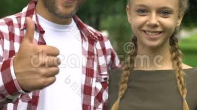 单身父亲和十几岁的女儿微笑着，竖起大拇指，家庭幸福