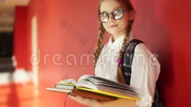 一个戴眼镜的可爱女孩的肖像。 女学生手里拿着书，<strong>背着</strong>一个<strong>书包</strong>，背到
