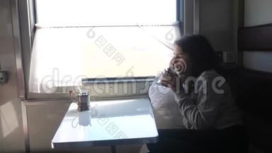 铁路旅行概念。 小女孩望着窗外，在车厢里喝茶。 穿深色衣服的女孩喝酒