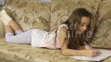 可爱的女孩躺在沙发上画画