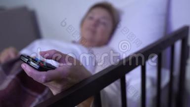 躺在病床上的妇女，在电视上转换频道，在医院的个人病房