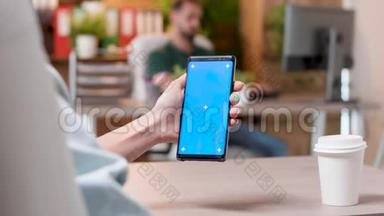 女人手里拿着一部智能手机，上面有一个蓝色屏幕的独立模拟